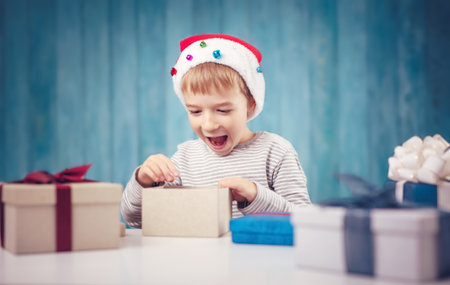 Cute child sitting at the table and opening giftboxesの写真素材