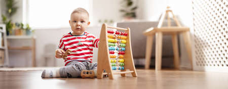Cute child sitting on the floor in the room and playing with toys.の写真素材
