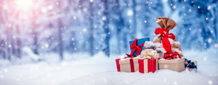 Pile of presents lying on the fresh snow in winter in forest. Gifts in wintertime outdoors. Christmas conceptの写真素材