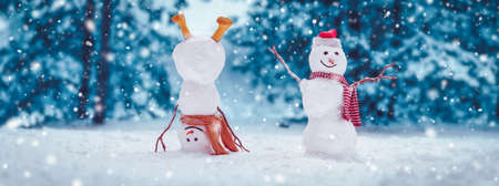 Cheerful snowmen standing in magical winter forestの写真素材