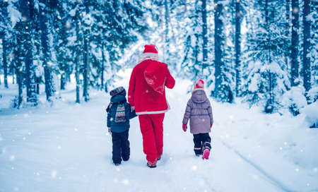 Santa Claus walking with children in the snowy forestの写真素材