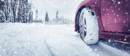 Panoramic view of the red car on the snowy road in snowfall.の写真素材