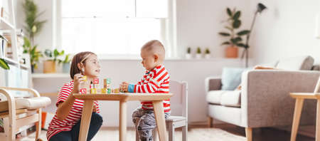 Sister teaching little brother letters by using cubes with symbols indoors.の写真素材
