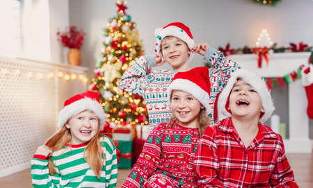 Happy children sitting in the living room at home in christmas pajamasの写真素材