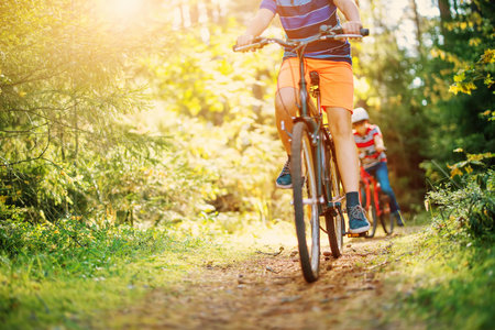 Children on a bicycles in the forest in early morning.の写真素材