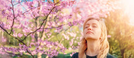 Young woman standing in the garden and breathing a fresh air.の写真素材