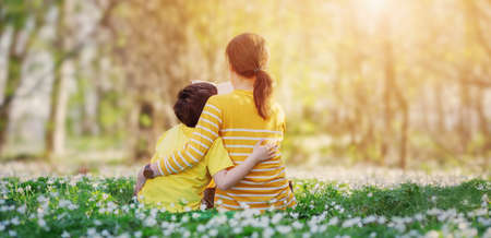 Mother and her son sitting n on the beautiful spring field in the sunny park.の写真素材