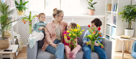 Cute cildren and their mother sitting with buncheson the sofa.の写真素材
