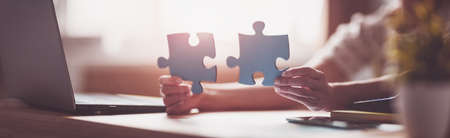 Woman holding pieces of puzzle in the office