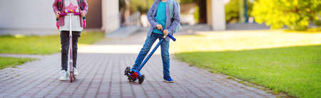 Girl and boy riding scooters from school.