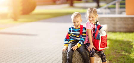 Boy and girl sitting on the stone near the schoolの写真素材