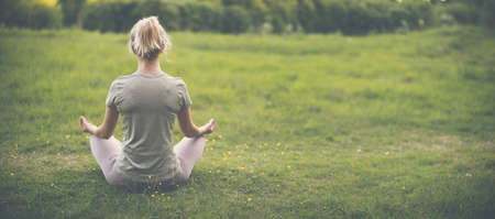 Woman sitting in active wear in lotus position in nature.の写真素材