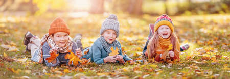 Group of children lying onthe ground in autumnal parkの写真素材