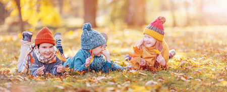 Group of children lying onthe ground in autumnal parkの写真素材