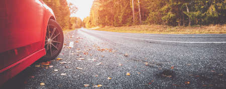 Red car on the autu asphalt road in countrysideの写真素材