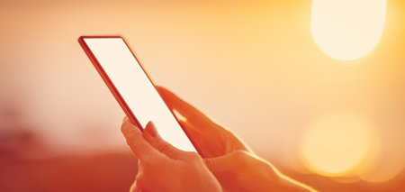 Woman hands holding smartphone at outdorrs in the eveningの写真素材