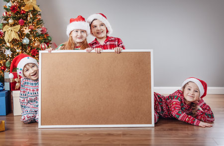 Four children indoors with empty banner on Christmas holiday.の写真素材