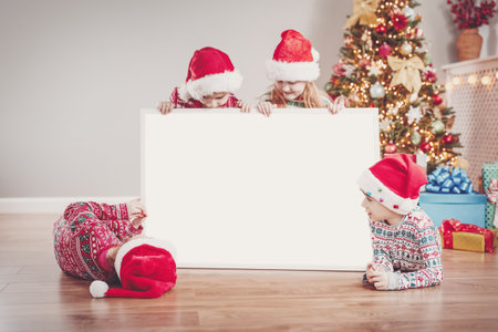 Four children indoors with empty banner on Christmas holiday.の写真素材