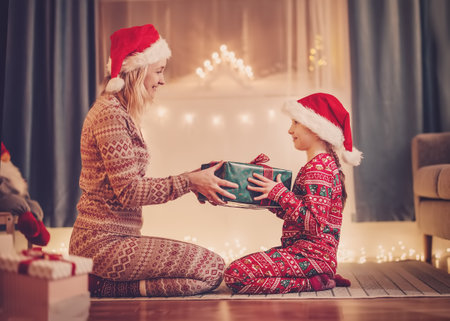Mom and daughter indoors giving present box each other in Christmas eve.の写真素材
