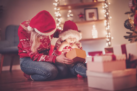 Mother and son indoors looking inside of gift box in Christmas eve.の写真素材
