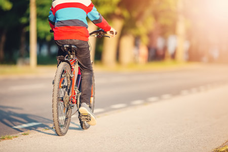 Boy riding a bike on the sidewalk along asphalt road.の写真素材
