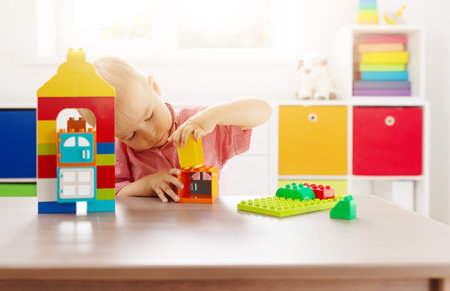 Cute child sitting at the table and playing with constructor.の写真素材