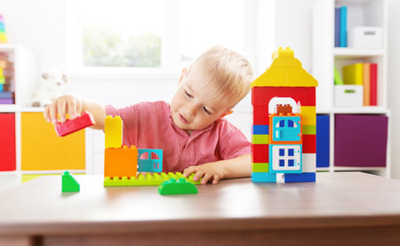 Cute child sitting at the table and playing with constructor.の写真素材