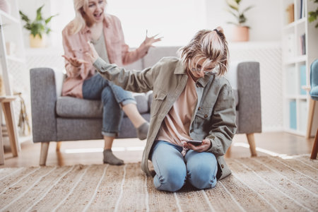 Mother arguing with her daughter chatting on smartphone.の写真素材