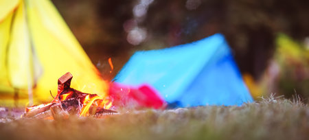 Closeup view of the fireplace near colourful tents in wilderness park.の写真素材