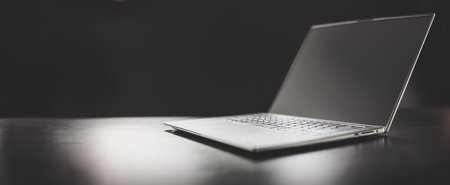 Grey laptop on the dark table on the black background.の写真素材