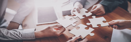 Buisnesswomen and buisnessmen working together while putting together puzzles.の写真素材