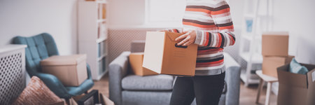 Woman carrying cardboard box in her handsの写真素材