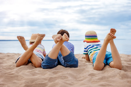 Three children lying on the sea beach in sunny day.の写真素材