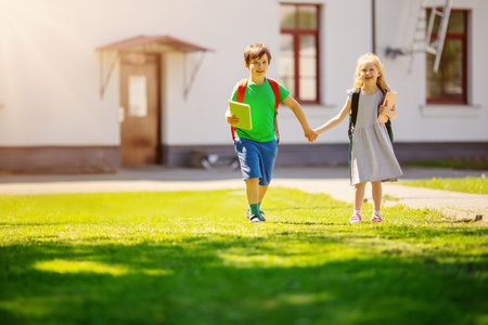 Boy and girl by holding hands going from school together.の写真素材
