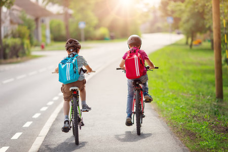 Two boys with backpacks on bicycles going to school.の写真素材