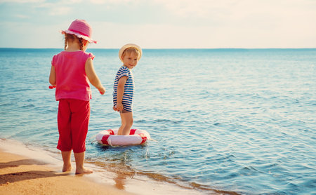 Cute boy and girl playing with lifebouy on the sea beach.の写真素材