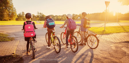 Boys and girl riding by bicycle to school together.の写真素材