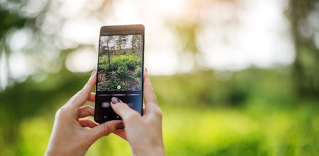 Woman making photo on the smart phone of nature outdoorsの写真素材