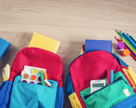 Colourful backpacks lying on the table filled by notebooks and stationery.の写真素材