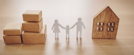 Figurines of family, house and carton boxes standing on the table indoors.