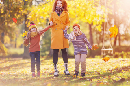 Mother with son and daugther playing in autumnal park.の写真素材