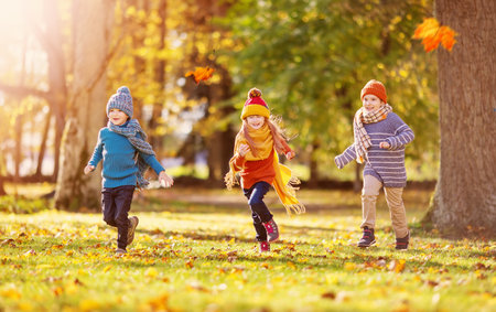 Children running and playing in the autumnal natural park.の写真素材