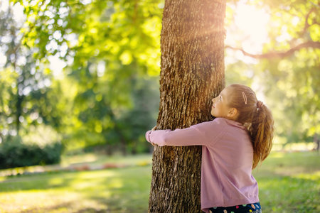 Cute little girl hugging tree in the natural park.の写真素材