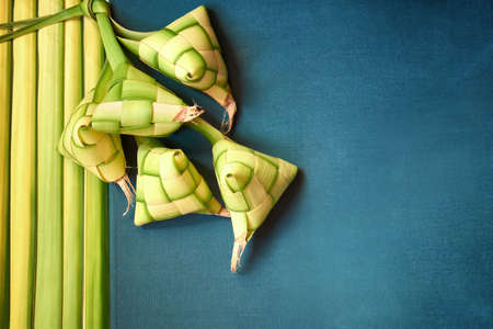 Hari Raya ketupat or Malay rice dumpling isolated on green background and palm leaves. Traditional Malay food during Ramadan and eid mubarak.の写真素材