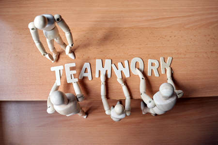 Group of wooden mannequin forming the text TEAMWORK alphabet on tableの写真素材