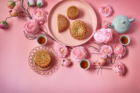 Mid autumn festival.Moon cake decorated with pink flower with teapot and cup of tea.の写真素材