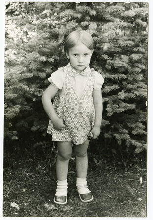 USSR - CIRCA 1986: An antique photo shows little girl standing under the treeのeditorial素材