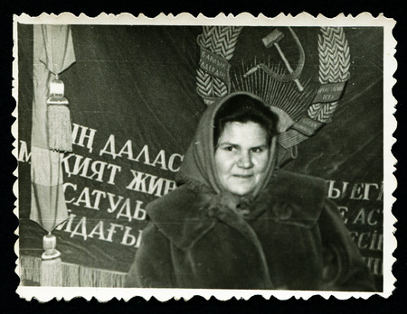 USSR - CIRCA 1970s: An antique photo shows  woman in a scarf standing against the background hammer and sickle, USSR, circa 1970sのeditorial素材