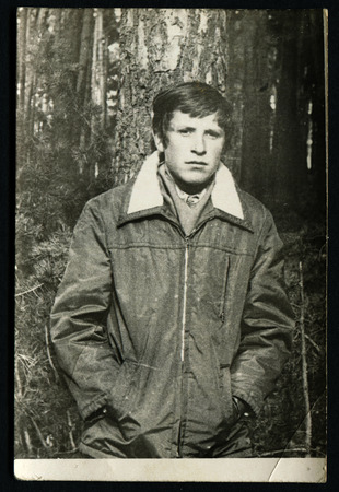 USSR - CIRCA 1970s: An antique photo show young man in a jacket in the woods near a treeのeditorial素材