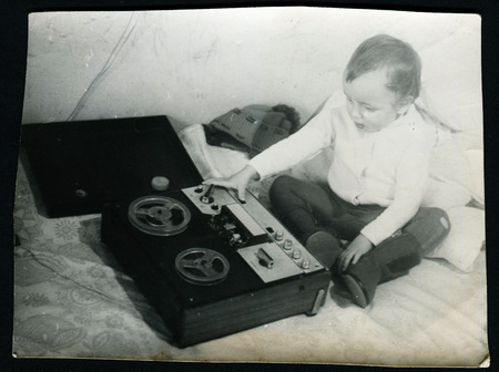 Ussr - CIRCA 1980s: An antique Black & White photo show little boy sitting near the tapeのeditorial素材